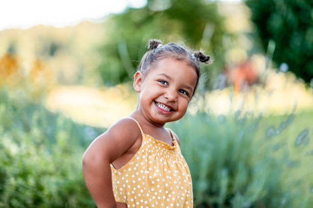 Portrait of cute little girl outdoors Portrait of a cute little cheerful mixed race girl in a yellow summer rummper. girls stock pictures, royalty-free photos & images