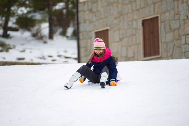 kleines mädchen rutscht mit schneeschlitten - snow dune stock-fotos und bilder