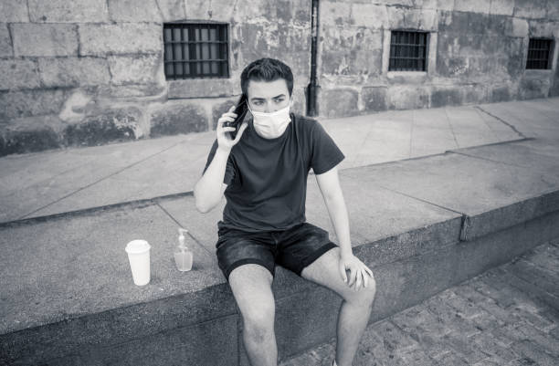 istock Young man in city street with protective mask using hand sanitizer and video calling friends and family. Stay connected, stop the coronavirus spread and The New Normal after COVID-19 Outbreak. 1268683021