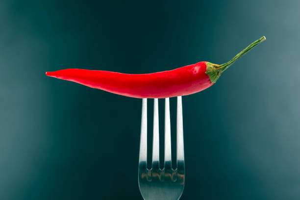 istock Red hot pepper with fork close-up on dark background. Healthy vegetable food and vitamins 1268683035