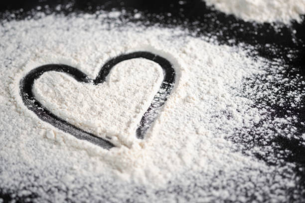Hand drawn heart on table sprinkled with confectionery flour
