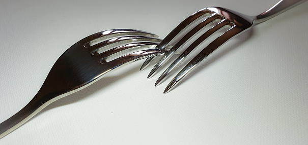 Two intertwined forks on white background