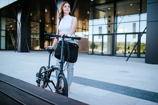 Businesswoman with her folding bike going to work