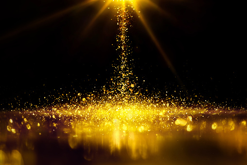 Golden glitter spatter are bokeh lighting texture blurred abstract background for anniversary celebration.
