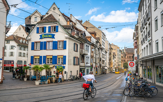 Basel Switzerland , 29 June 2020 : Woman speeding on a bicycle and tramline and ancient houses street view in Basel old town Switzerland