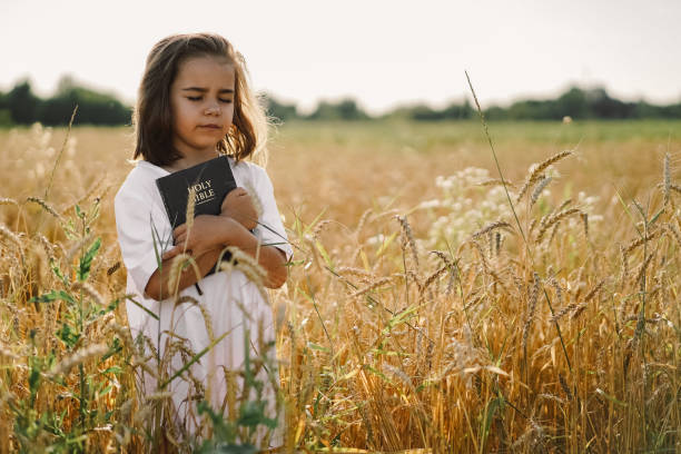 la chica tiene la biblia en sus manos. leyendo la santa biblia en un campo. concepto de fe, espiritualidad y religión - christ child fotografías e imágenes de stock