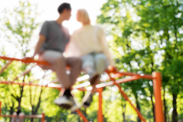 Out of focused image of couple on a playground Out of focused image of couple on a playground in a city park teenager couple child blond hair stock pictures, royalty-free photos & images