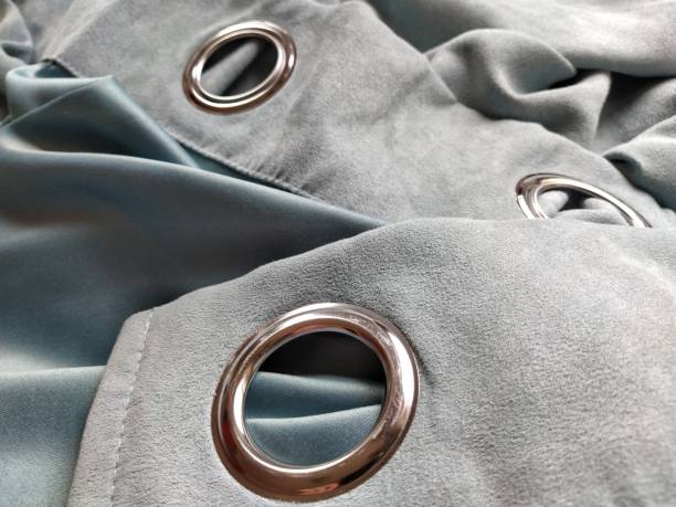 two metal eyelets on gray-blue velvet curtains stock photo