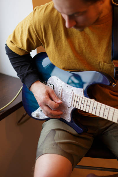 istock A young guy plays an electric guitar sitting by the window 1268703736