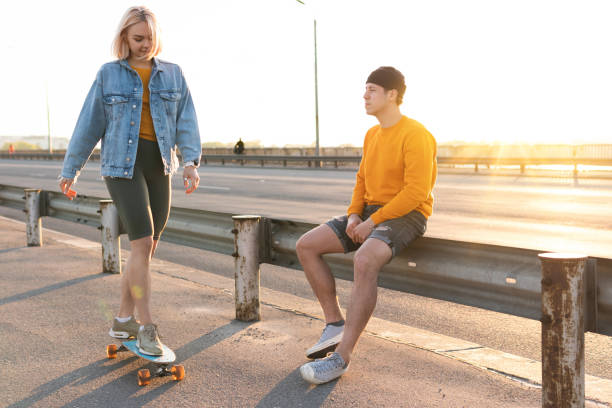 istock Couple with a longboard on the bridge during the sunset 1268704842