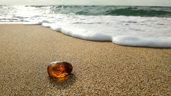 A piece of natural Baltic amber on the sand