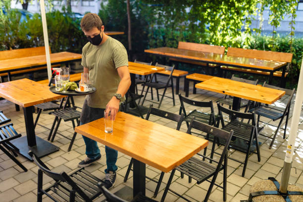 istock Waiter collecting empty glasses after first customer during reopening coffee shop 1268711889