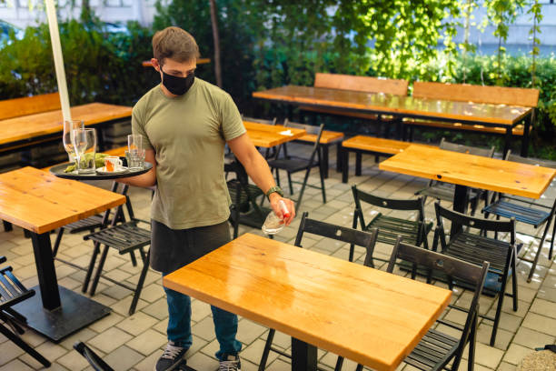 istock Waiter using disinfection product to clean a table after customer in his cafeteria 1268711901
