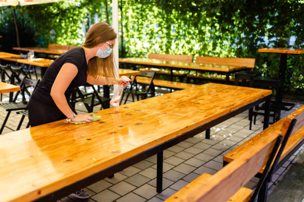 istock Waitress cleaning table with disinfection liquid and preparing cafeteria for opening 1268711946