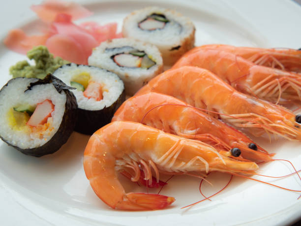 istock Delicious Boiled Shrimps with Maki Rolls Served on Plate 1268712114