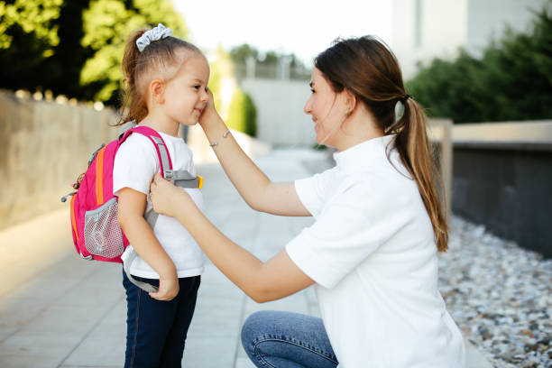 madre preparando a su hijo para la escuela frente a su casa - back to school young women cheerful happiness fotografías e imágenes de stock