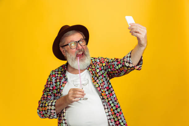 istock Senior hipster man wearing eyeglasses posing on yellow background. Tech and joyful elderly lifestyle concept 1268721678