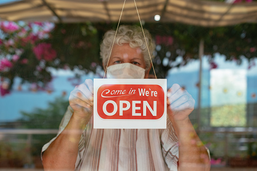 Woman Wearing Face Mask Holding Open Sign in a Small Business Shop