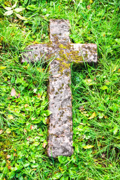 древний каменный крест в траве - old cross shape stone weathered стоковые фото и изображения