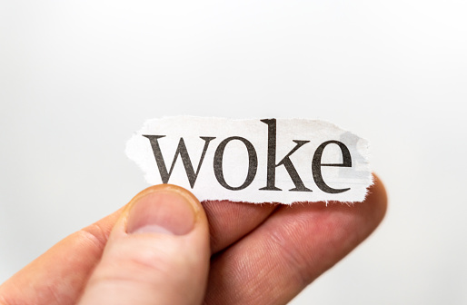 Macro image of a person holding up the word 'woke'.