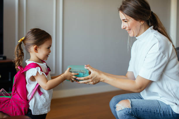 mamma che mette la scatola del pranzo con cibo sano nello zaino - little girls small eating breakfast foto e immagini stock