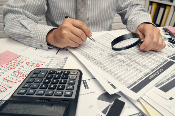 istock Business analysis and accounting concept - businessman working with document, spreadsheet, using calculator, tablet pc. Office desk closeup. 1268727885
