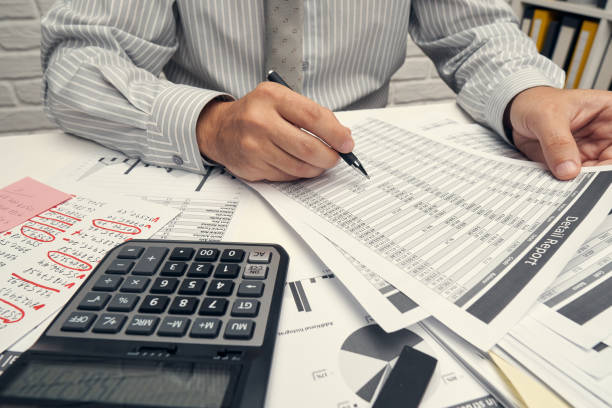 istock Business analysis and accounting concept - businessman working with document, spreadsheet, using calculator, tablet pc. Office desk closeup. 1268727908