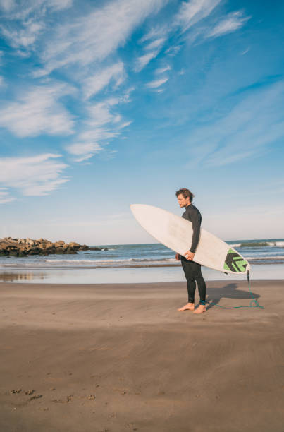 istock Surfer standing in the ocean with his surfboard. 1268733218