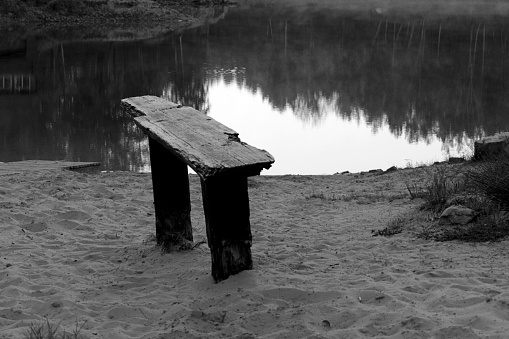 old wooden bench on the bank of a pond
