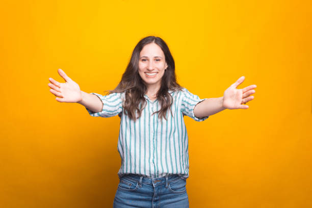 Young woman is smiling at the camera with arms wide open for hugs stock photo