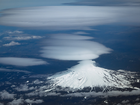 Lenticular clouds are indicative of high winds at altitude. In this photo lenticular clouds form above Mount Hood as a winter storm approaches.