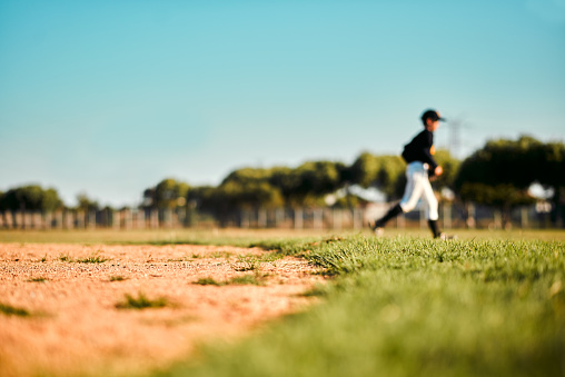 Baseball, sports and fitness fast run of a sport player running on outdoor field in a game. Training, workout and exercise of a young athlete with focus and freedom from runner speed in the sun