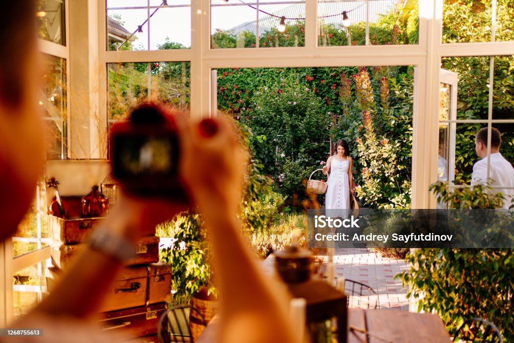 photographer takes picture of woman expecting baby a professional photographer takes a picture of a woman expecting a baby in the backyard garden. it is a tradition to take photos as a souvenir. pregnancy photo shoot Photo Shoot Stock Photo