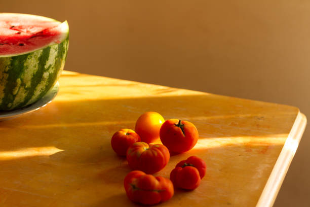 Watermelon and tomatoes on a wooden table with sunlight