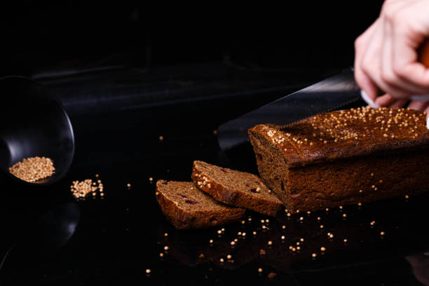 黒い背景に自家製の黒パン。セクションの写真。 - brown bread bread cutting board full length ストックフォトと画像