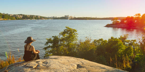 High angle shot of a woman wearing striped sweater while sitting with her cute dog on jetty by the sea.
