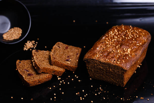 黒い背景に自家製の黒パン。セクションの写真。 - brown bread bread cutting board full length ストックフォトと画像