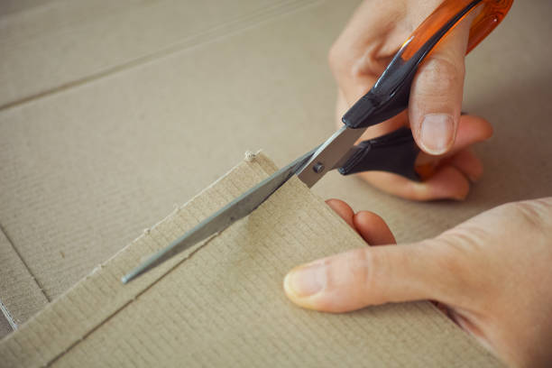 istock Woman cutting cardboard with scissors 1268788869