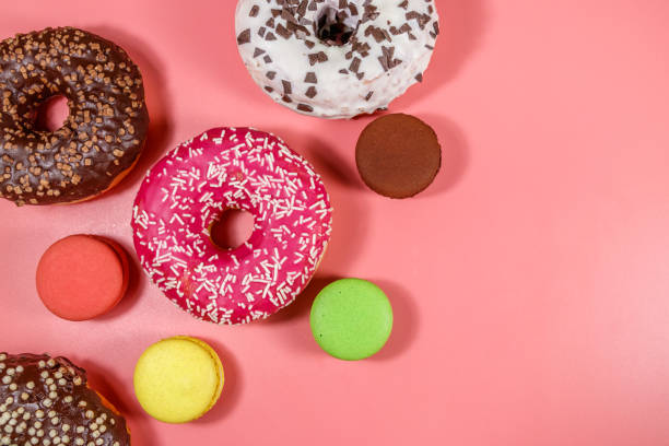 istock Tasty donuts and macaroons on pink background. Top view 1268789968