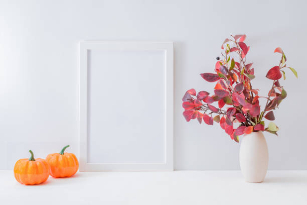 Home interior with decor elements. Mockup with a white frame, colorful autumn leaves in a vase on a light background