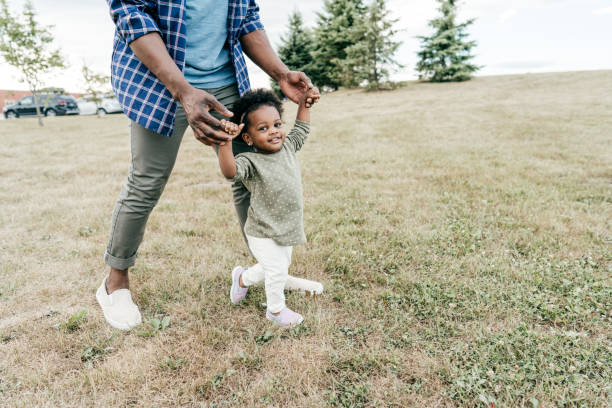 кусочек жизни - аутентичный момент семьи с милым малышом - family grass toddler african descent стоковые фото и изображения