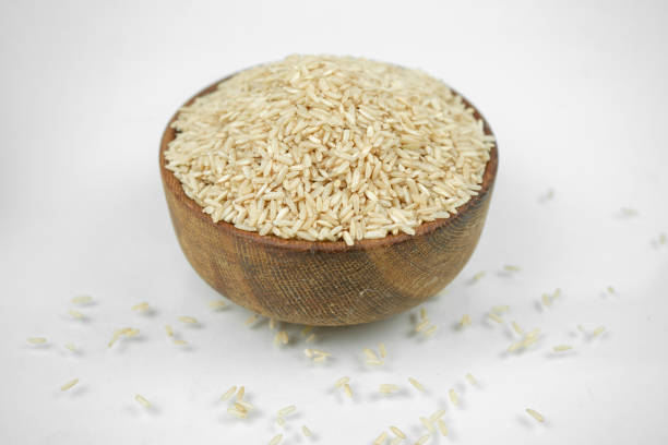 istock brown rice in a wooden bowl isolated on white, horizontal studio shot 1268805635