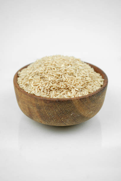istock brown rice in a wooden bowl isolated on white, vertical studio shot 1268806694