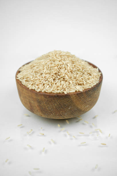 istock brown rice in a wooden bowl isolated on white, vertical studio shot 1268806730