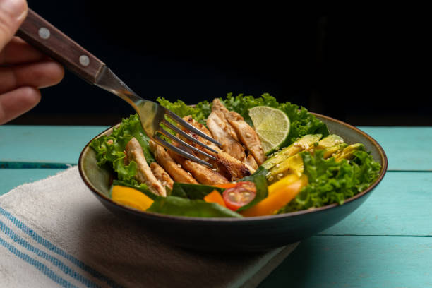 istock Grilled chicken salad with avocado and vegetables on turquoise background 1268816125