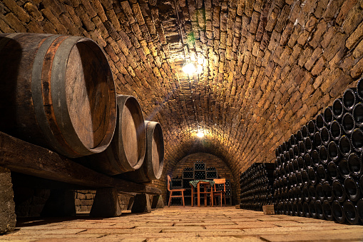 wooden old barrels in the rustic wine cellar with brick walls in hajos hungary .