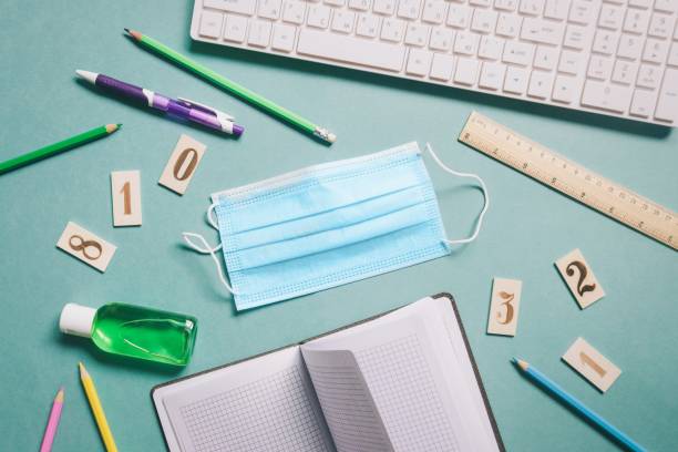 Flat lay photo work table. Computer keyboard, disposable face mask, sanitizer gel. Remote work or online education concept