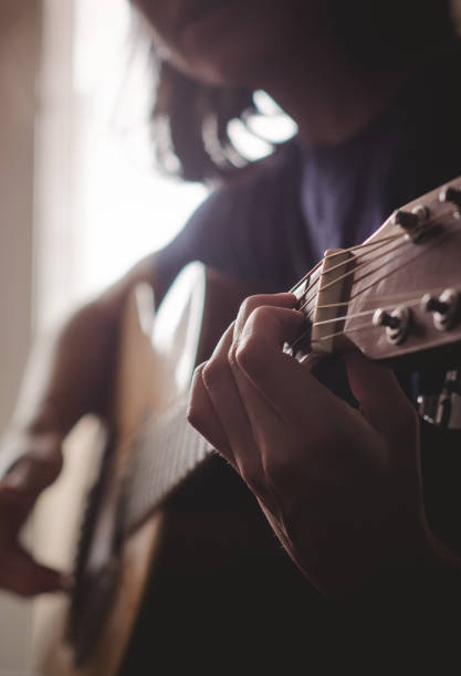 das mädchen spielt gitarre im raum. dim licht aus dem fenster - bass guitar stock-fotos und bilder