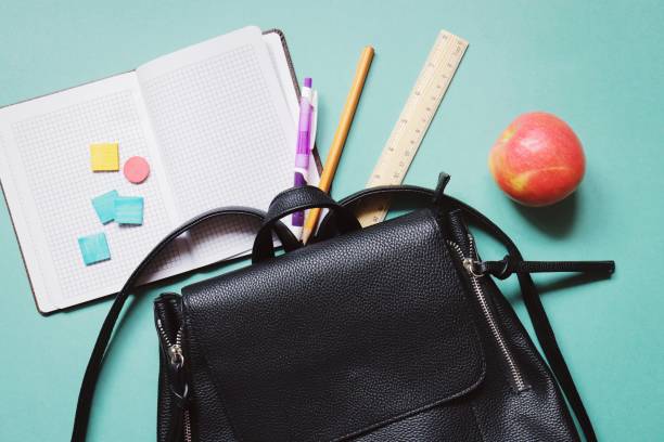 istock Flat lay back to school composition. Backpack, open paper notebook, pen, pencil, wooden ruler and red apple on a green background. Education concept 1268830101