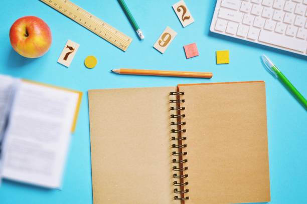 istock Open book, paper notebook, pencil, pen, ruler, computer keyboard and red apple on a blue background. Back to school concept. Flat lay table photo 1268849054